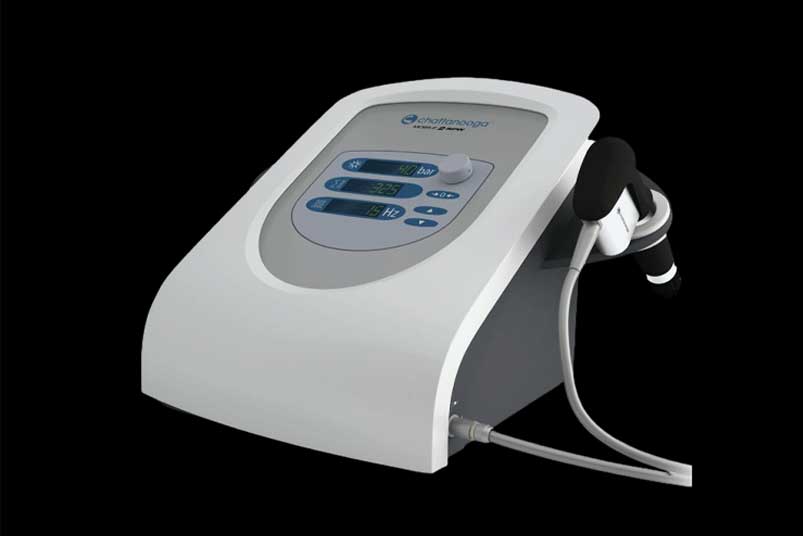 Doctor using touchscreen of modern medical equipment during physiotherapy treatment