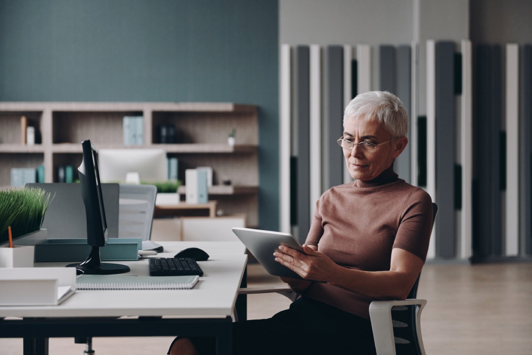 Concentrated senior businesswoman using digital tablet while working in the office