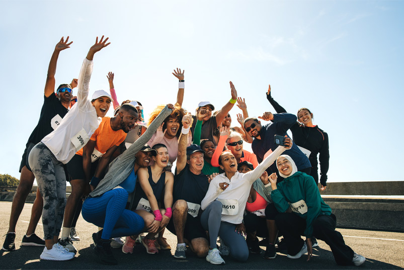 A vibrant group of runners pose joyfully together, showcasing camaraderie and community spirit. This lively shot of a neighborhood running club captures their celebration after a successful race.