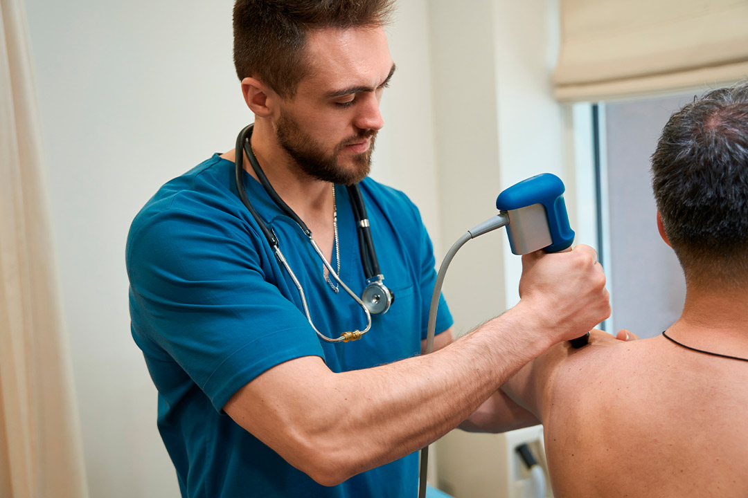 health specialist doing shockwave therapy over knee
